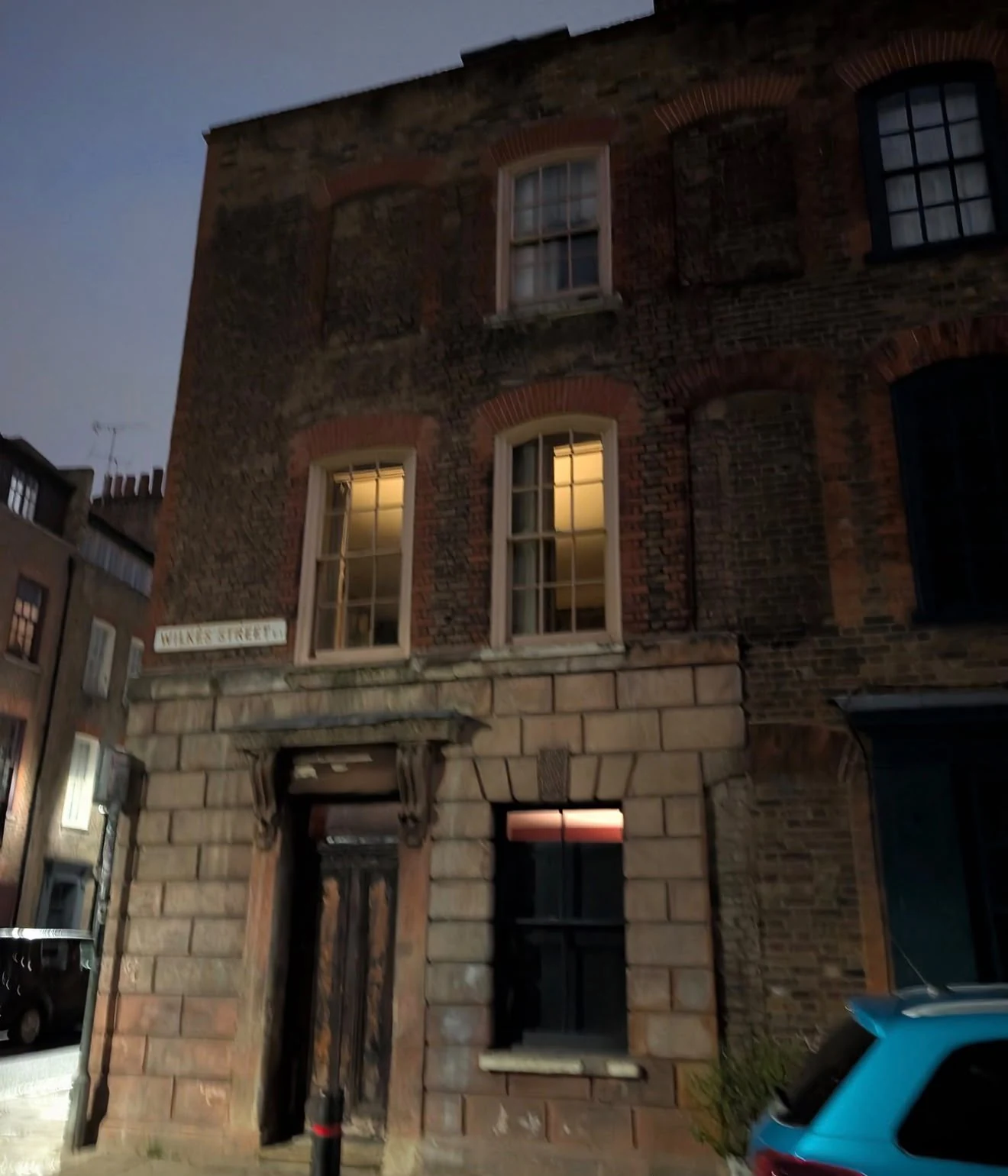 Historic brick building and Mitre Square street sign photographed at dusk during a Jack the Ripper tour.